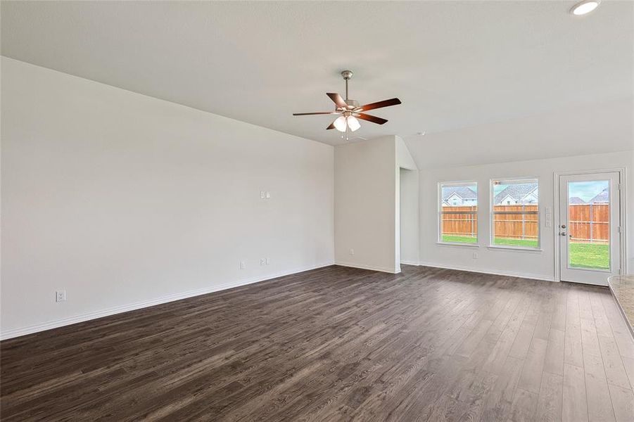 Empty room with dark hardwood / wood-style floors, lofted ceiling, and ceiling fan