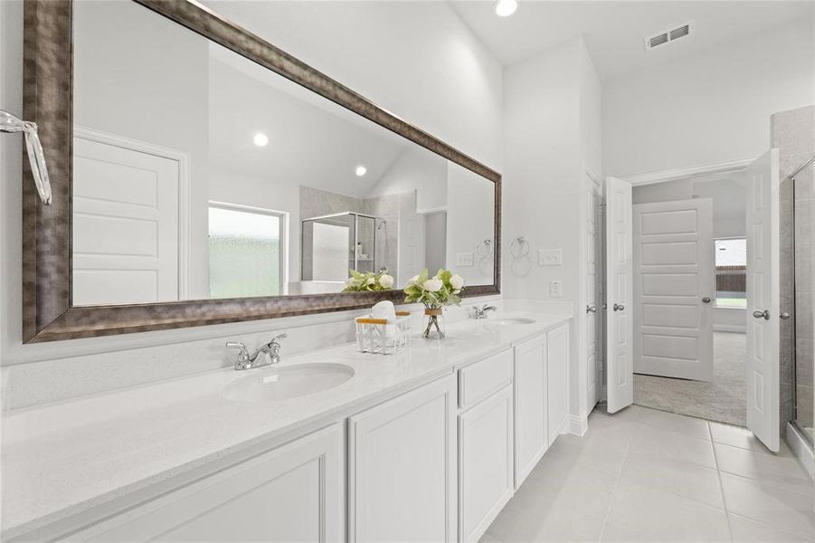 Bathroom with tile patterned floors, a sink, a shower stall, visible vents, and double vanity