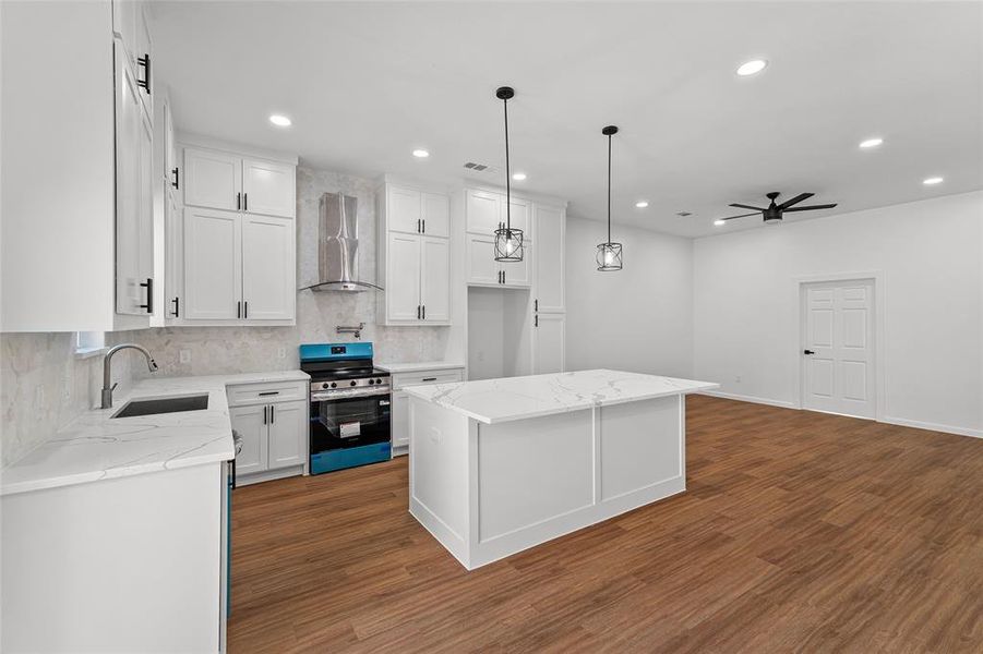 Kitchen featuring a center island, stainless steel range with electric cooktop, backsplash, light stone counters, and ceiling fan