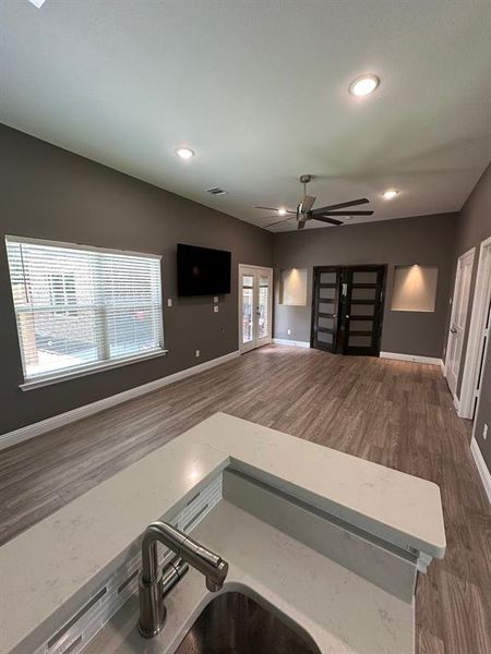 Kitchen with a ceiling fan, recessed lighting, dark wood-style floors, open floor plan, and light stone countertops