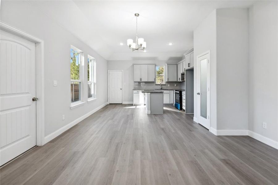 Unfurnished living room with a notable chandelier, light hardwood / wood-style floors, and sink