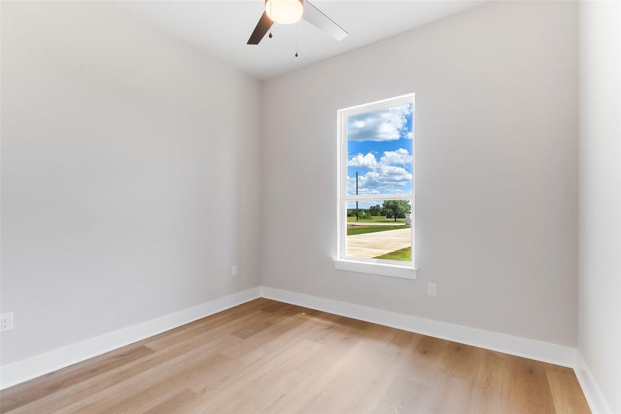 Empty room with a ceiling fan and light wood finished floors