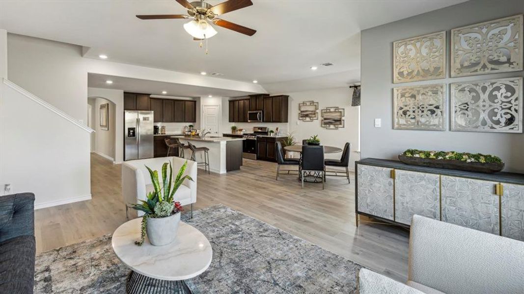 The property presents an open-concept living space featuring light-toned flooring and a ceiling fan