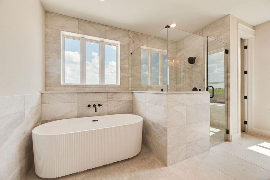 Bathroom featuring a stall shower, a freestanding bath, and tile walls