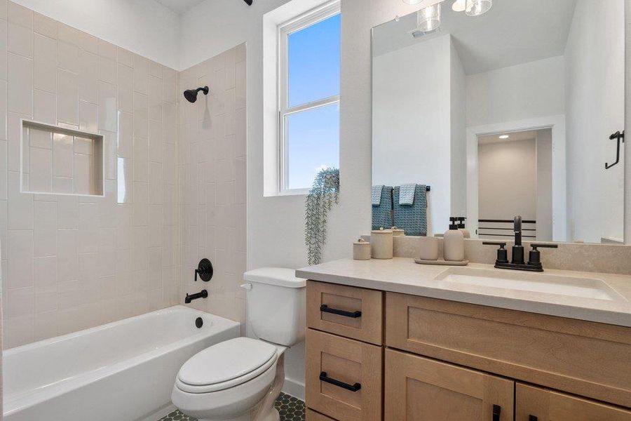 Bathroom featuring a light wood-finish vanity with a light countertop and integrated sink, matte black faucet, and a large mirror