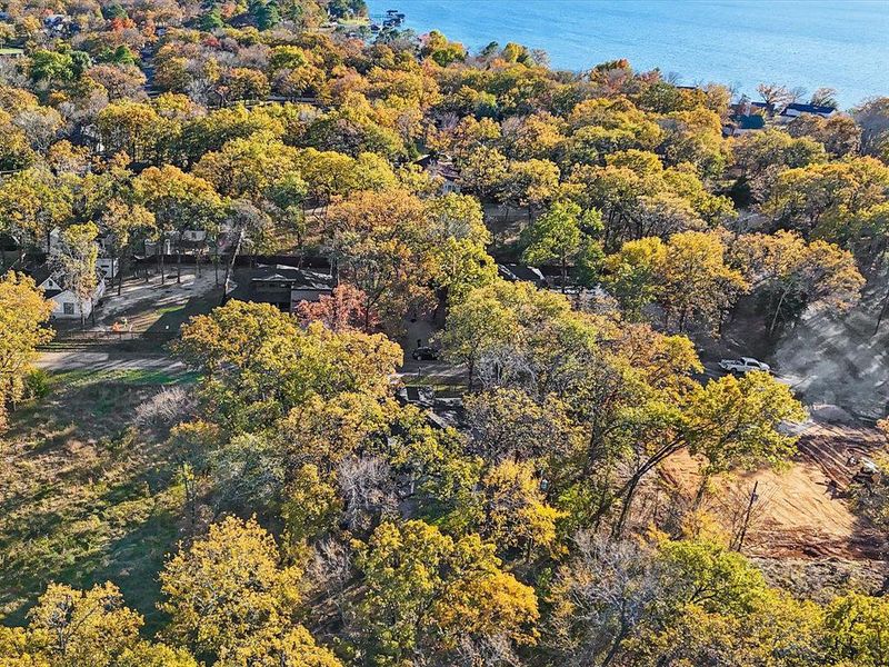 Aerial view of property and surrounding area featuring a forest and a large body of water