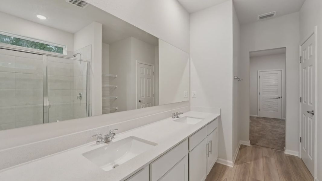Indulge in this Palm Coast sanctuary featuring dual quartz sinks, elegant cabinetry, and a serene spa shower.