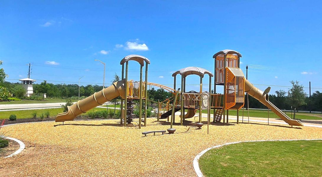 Community playground featuring multiple slides, climbing structures, swings, and a wood chip surface