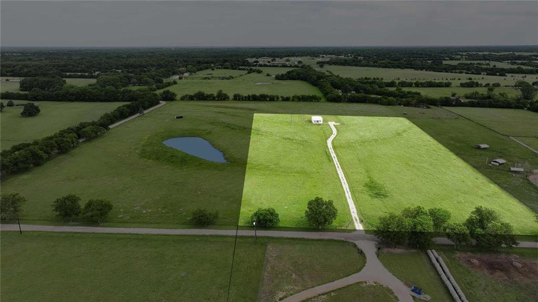 Expansive grass acreage featuring a winding driveway leading to a white structure