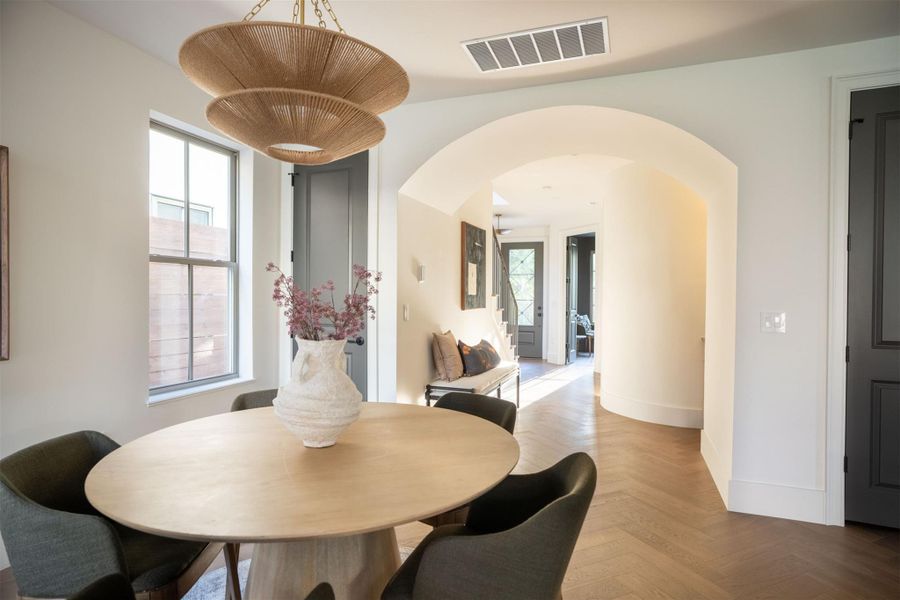 An elegant arched doorway transitions seamlessly into a hallway with classic herringbone wood flooring. An elegant arched doorway transitions seamlessly into a hallway with classic herringbone wood flooring.