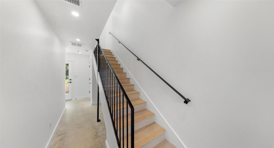 A bright third-level landing with a sleek metal railing — a light, airy connector between the home's living spaces. Model No. 105 Shown.