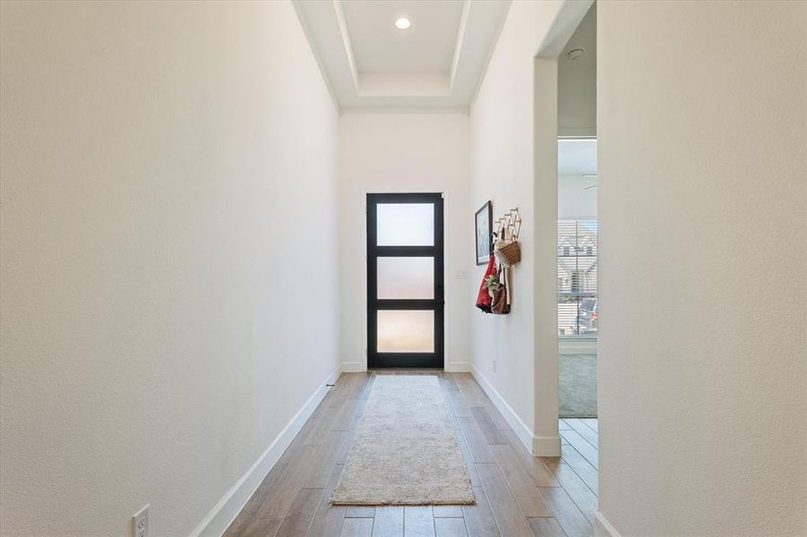 Doorway to outside featuring light wood finished floors and a raised ceiling Doorway to outside featuring light wood finished floors and a raised ceiling