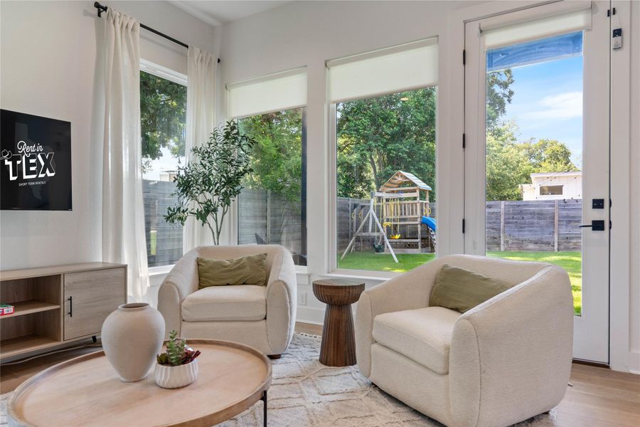 Large picture windows frame views of the private yard and garden playground.
