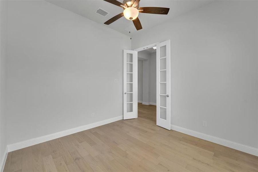 Unfurnished room with light wood-style flooring, french doors, and a ceiling fan
