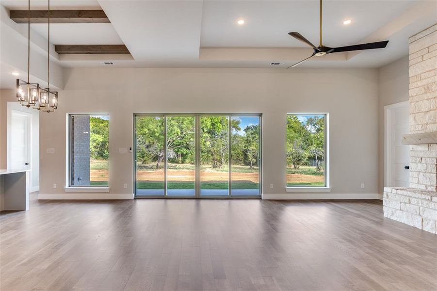 Unfurnished living room featuring light wood finished floors, recessed lighting, healthy amount of natural light, a chandelier, and a raised ceiling Unfurnished living room featuring light wood finished floors, recessed lighting, healthy amount of natural light, a chandelier, and a raised ceiling