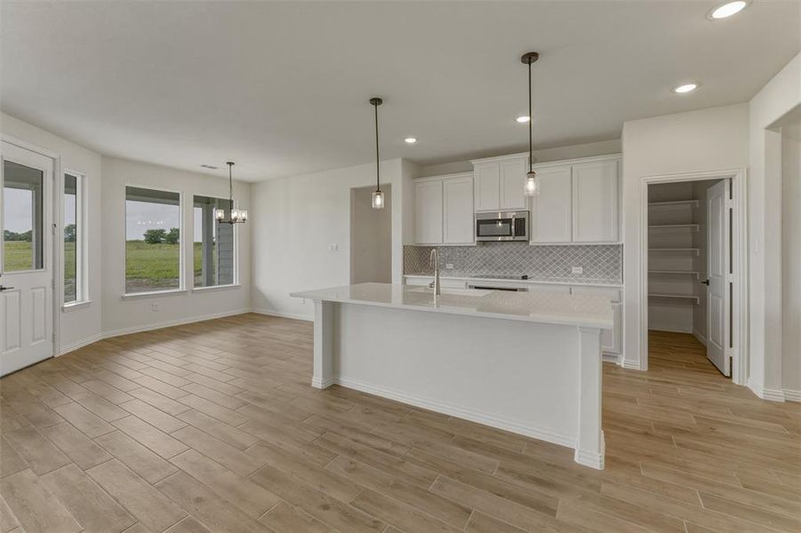Open-concept kitchen and dining area featuring wood-finish flooring, recessed lighting, and a kitchen island with pendant lighting Open-concept kitchen and dining area featuring wood-finish flooring, recessed lighting, and a kitchen island with pendant lighting