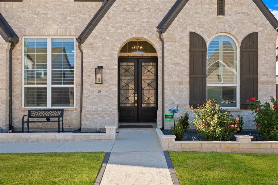 View of exterior entry with brick siding, french doors, and a lawn View of exterior entry with brick siding, french doors, and a lawn