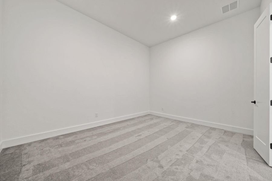 Empty room with light carpet and recessed lighting