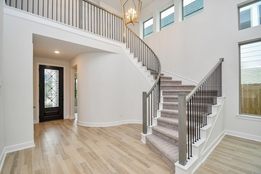 A grand foyer with soaring ceilings and a dramatic staircase leading to the upper level.