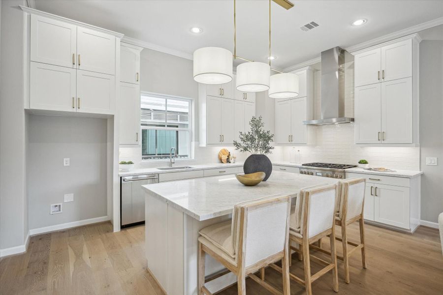 Kitchen has porcelain backsplash, gold island pendant light, and engineered white oak wood flooring.