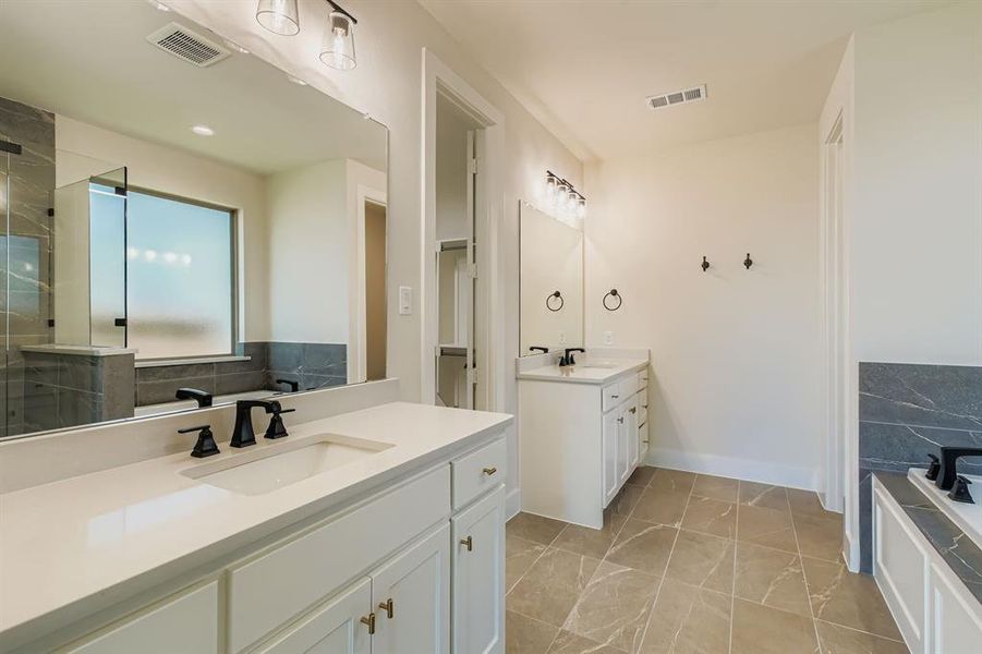 Full bath featuring two vanities and a tile shower