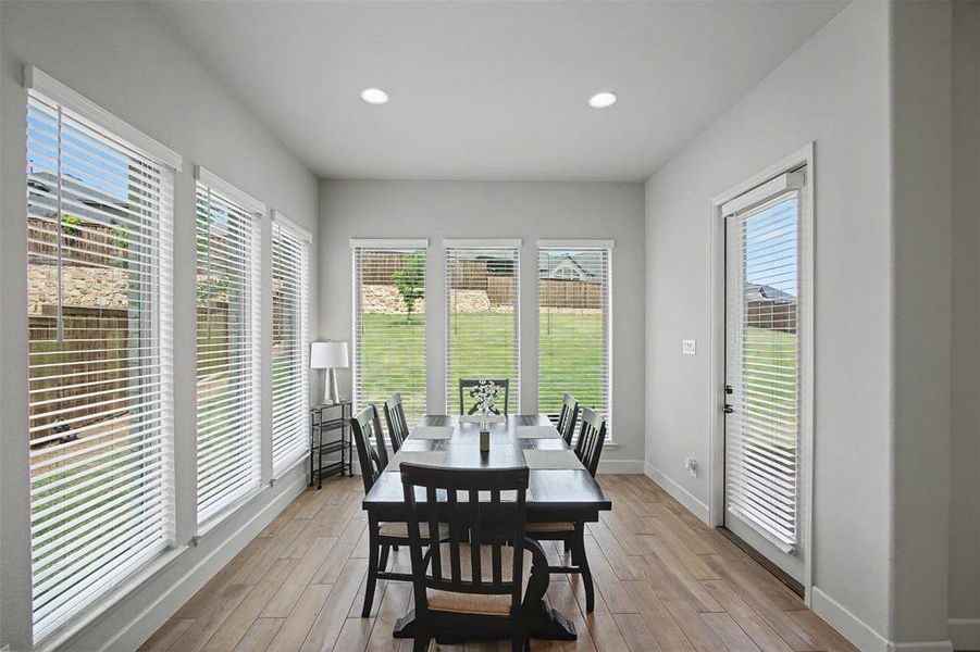 Spacious dining area featuring wood-finish flooring, recessed lighting, and multiple windows with horizontal blinds