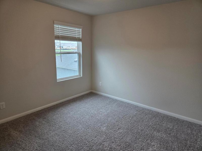 Neutral-toned wall finishes complemented by a window with white blinds and grey carpeting
