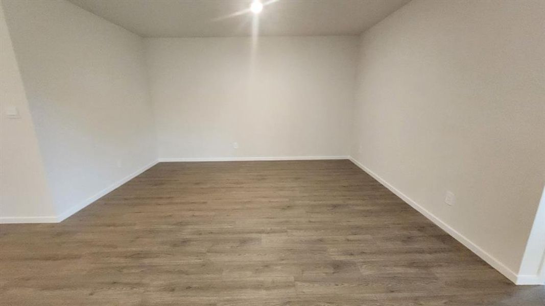 Spacious room featuring wood-finish flooring, white baseboards, and neutral wall tones