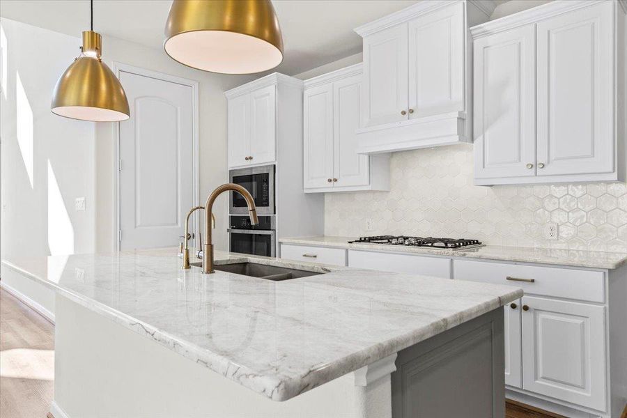 Kitchen featuring backsplash, light stone counters, white cabinets, and pendant lighting Kitchen featuring backsplash, light stone counters, white cabinets, and pendant lighting