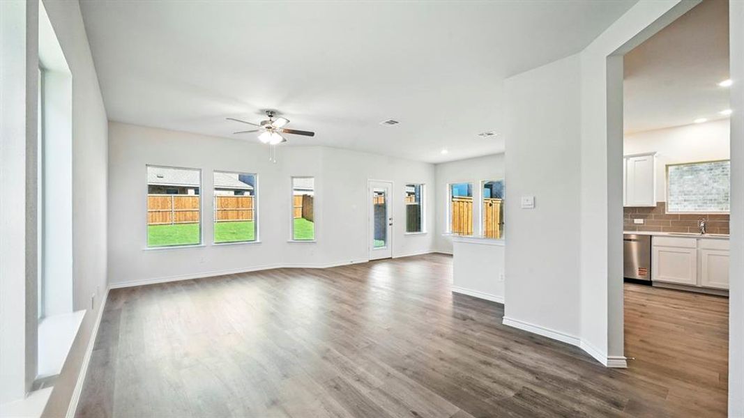 Unfurnished living room featuring dark wood-style floors, plenty of natural light, and ceiling fan