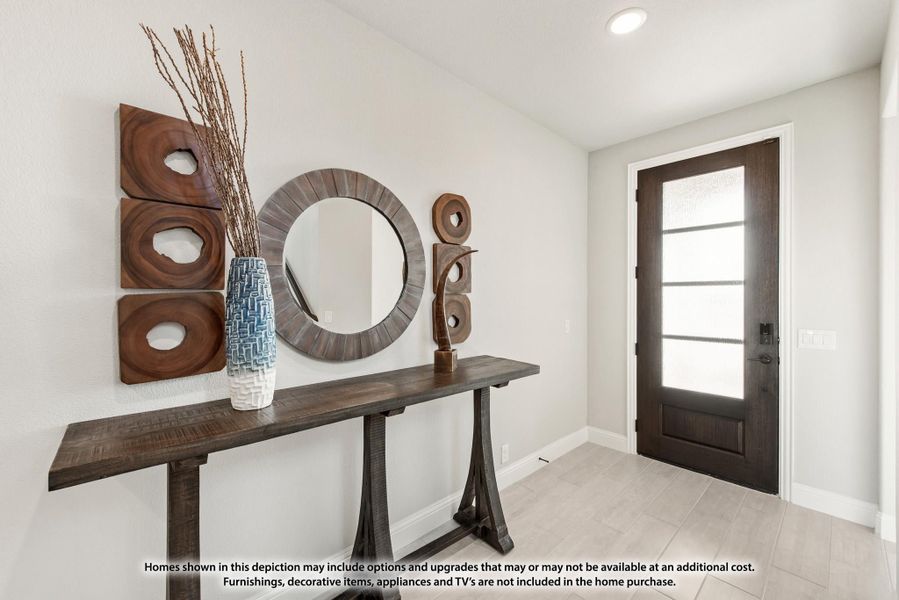 Entryway with dark wood console table, round mirror, wall art, and dark front door with glass panels