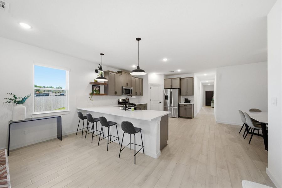 This photo showcases a modern, open-concept kitchen with sleek cabinetry, a large island with seating, stainless steel appliances, and bright natural light. The space flows seamlessly into a dining area, perfect for entertaining.