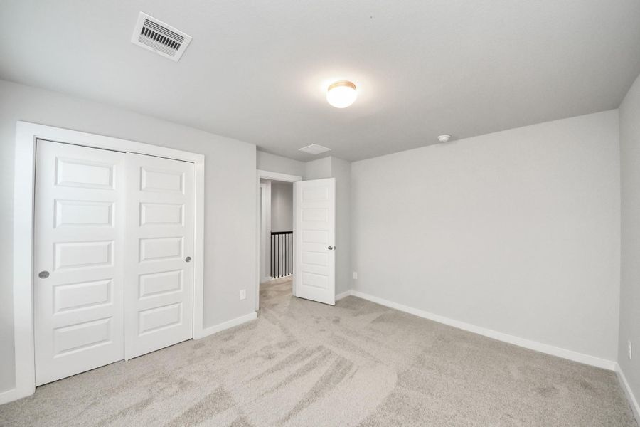 Secondary bedroom features plush carpeting, large windows that let in plenty of natural light, bright paint, and spacious closets. Sample photo of completed home with similar floor plan. Actual colors and selections may vary. Secondary bedroom features plush carpeting, large windows that let in plenty of natural light, bright paint, and spacious closets. Sample photo of completed home with similar floor plan. Actual colors and selections may vary.