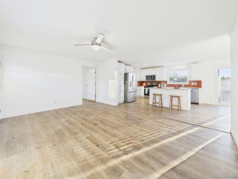 Family Room Wide plank floors and abundant sunlight define this spacious layout, where the living area flows seamlessly into the modern kitchen with a central island.
