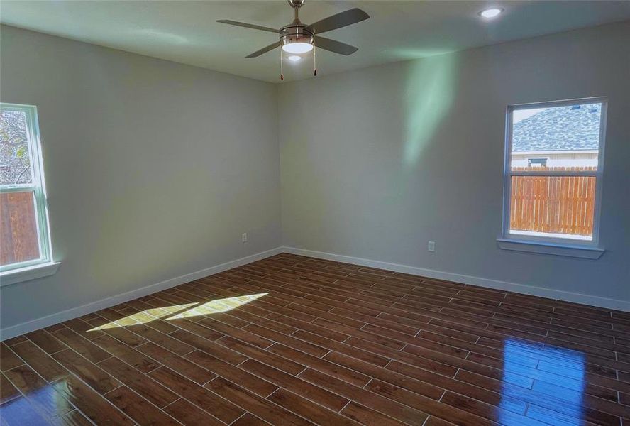 Empty room with ceiling fan and dark hardwood / wood-style flooring