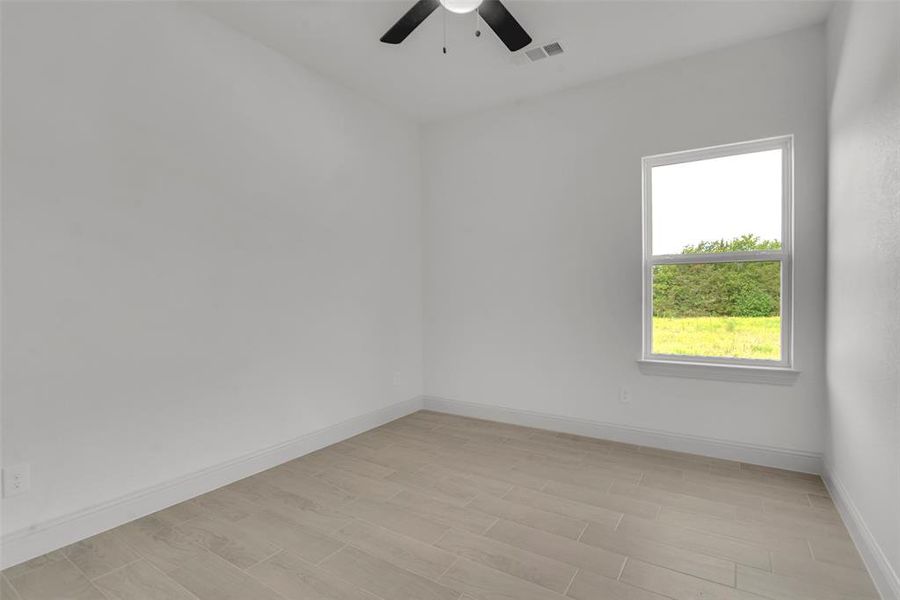 Empty room with a ceiling fan and light wood-style flooring Empty room with a ceiling fan and light wood-style flooring