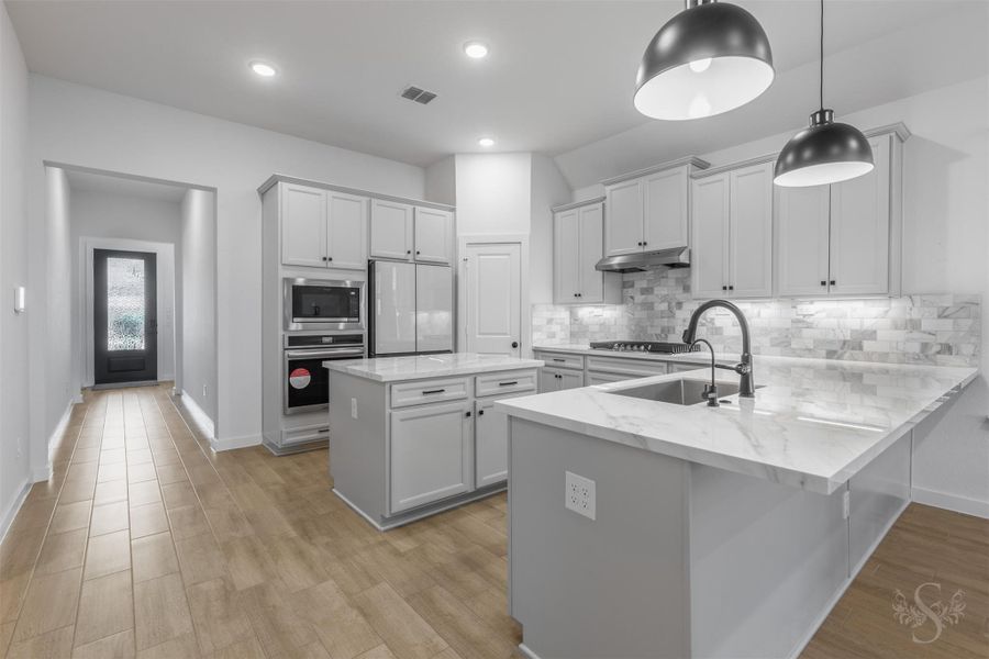This stunning chef’s kitchen boasts sleek porcelain countertops, soft gray cabinetry, and a striking marble look backsplash that adds elegance and texture. Pendant lighting and a spacious center island create the perfect blend of style and function for everyday living or entertaining. This stunning chef’s kitchen boasts sleek porcelain countertops, soft gray cabinetry, and a striking marble look backsplash that adds elegance and texture. Pendant lighting and a spacious center island create the perfect blend of style and function for everyday living or entertaining.