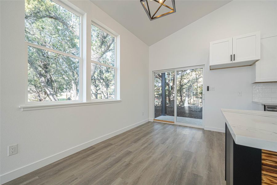 Unfurnished dining area featuring high vaulted ceiling, dark wood-type flooring, and a chandelier