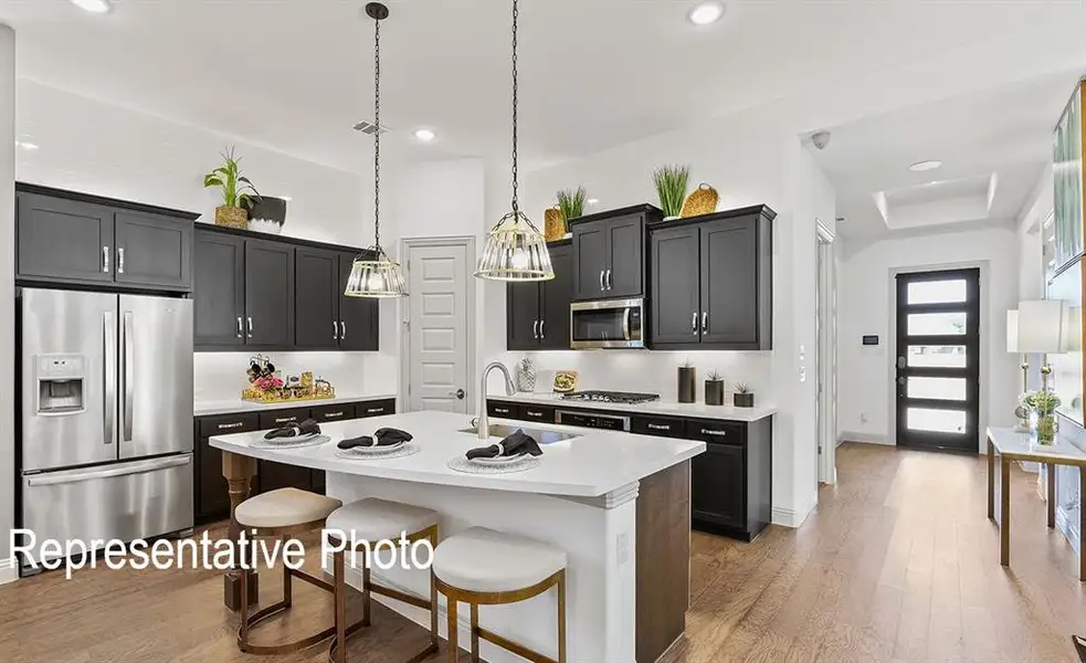 Open-concept kitchen featuring dark wood cabinetry, stainless steel appliances, and a central island with countertop seating Open-concept kitchen featuring dark wood cabinetry, stainless steel appliances, and a central island with countertop seating