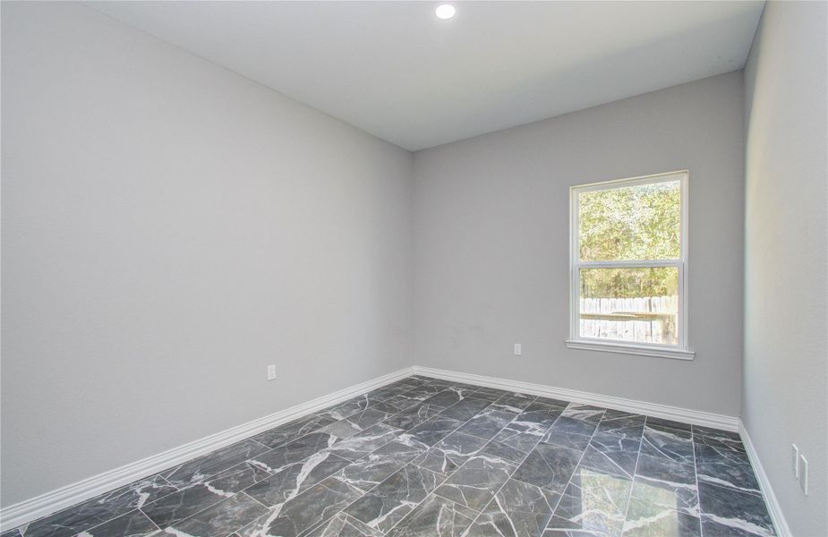 This room features modern gray walls, glossy marble-style flooring, and a large window offering natural light and a view of the outdoors, creating a bright, elegant space.