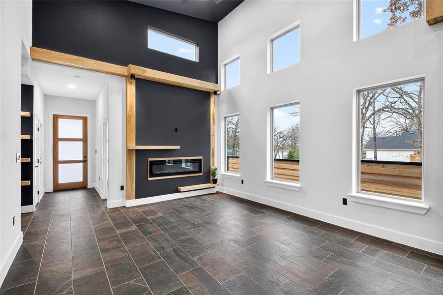 Unfurnished living room featuring a high ceiling and a glass covered fireplace