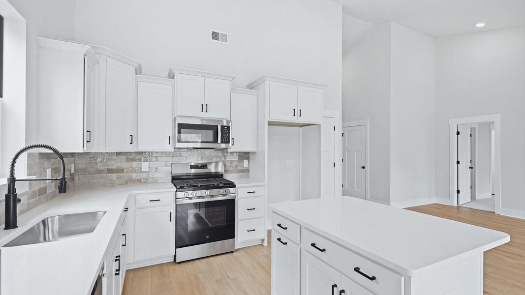 Well-designed kitchen with a center island and tasteful finishes that elevate everyday living by DRB Homes