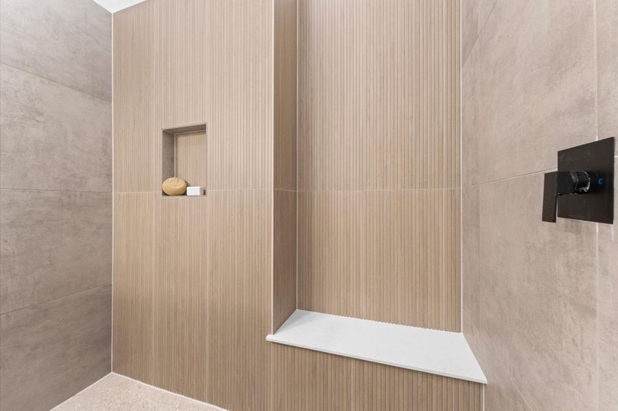 The luxurious primary ensuite features sleek modern finishes, a glass-enclosed shower with stylish tile, and a double-sink vanity topped with quartz countertops, complemented by two contemporary mirrors and lighting fixtures, creating a bright, elegant, and functional retreat.