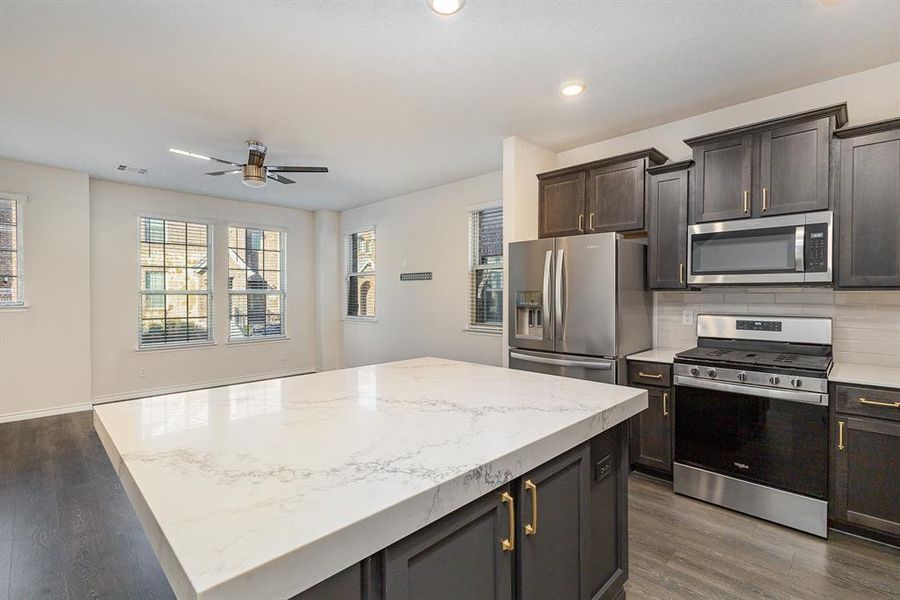 Kitchen with tasteful backsplash, dark hardwood / wood-style flooring, a kitchen island, and appliances with stainless steel finishes