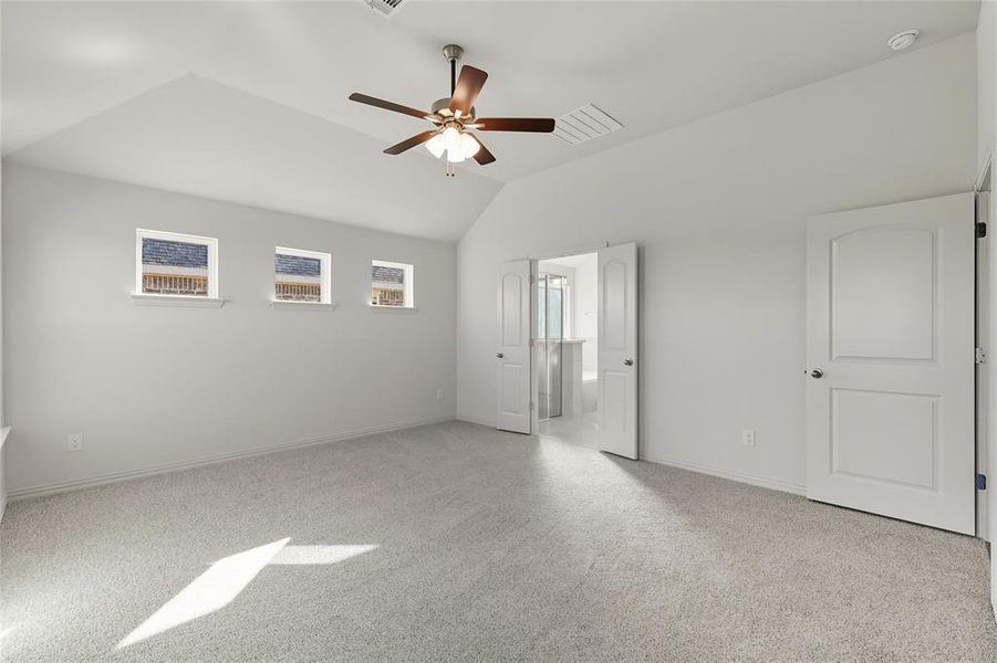 Unfurnished bedroom with light colored carpet, lofted ceiling, and a ceiling fan Unfurnished bedroom with light colored carpet, lofted ceiling, and a ceiling fan