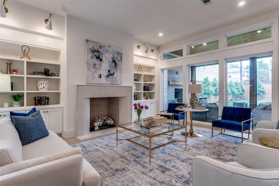 Living room featuring built in shelves, wood finished floors, a fireplace with flush hearth, and recessed lighting Living room featuring built in shelves, wood finished floors, a fireplace with flush hearth, and recessed lighting