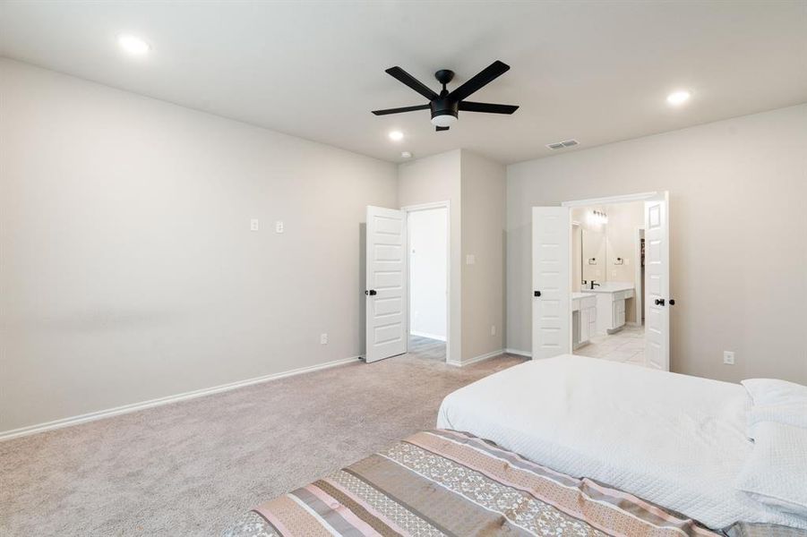 Bedroom with light colored carpet, ceiling fan, recessed lighting, and connected bathroom Bedroom with light colored carpet, ceiling fan, recessed lighting, and connected bathroom