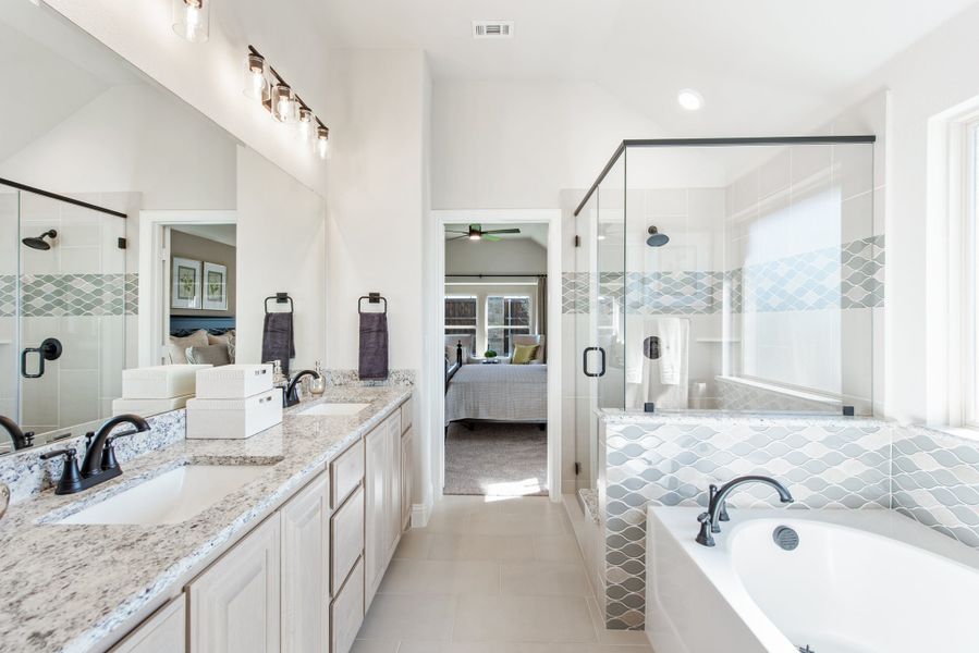 Master bathroom with double vanity, granite countertops, soaking tub, and glass walk-in shower with decorative tile Master bathroom with double vanity, granite countertops, soaking tub, and glass walk-in shower with decorative tile