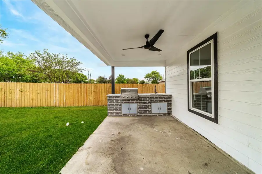 Fenced backyard featuring exterior kitchen, a patio, and a ceiling fan