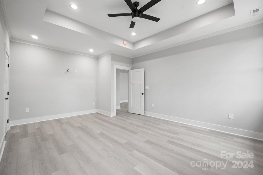 Primary bedroom with large ceiling fan and tray ceilings